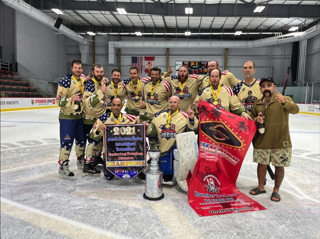 OneHockey adult tournament champions — Las Vegas — the Enduring Freedom Division team on the ice with the cup, medals and championship banner
