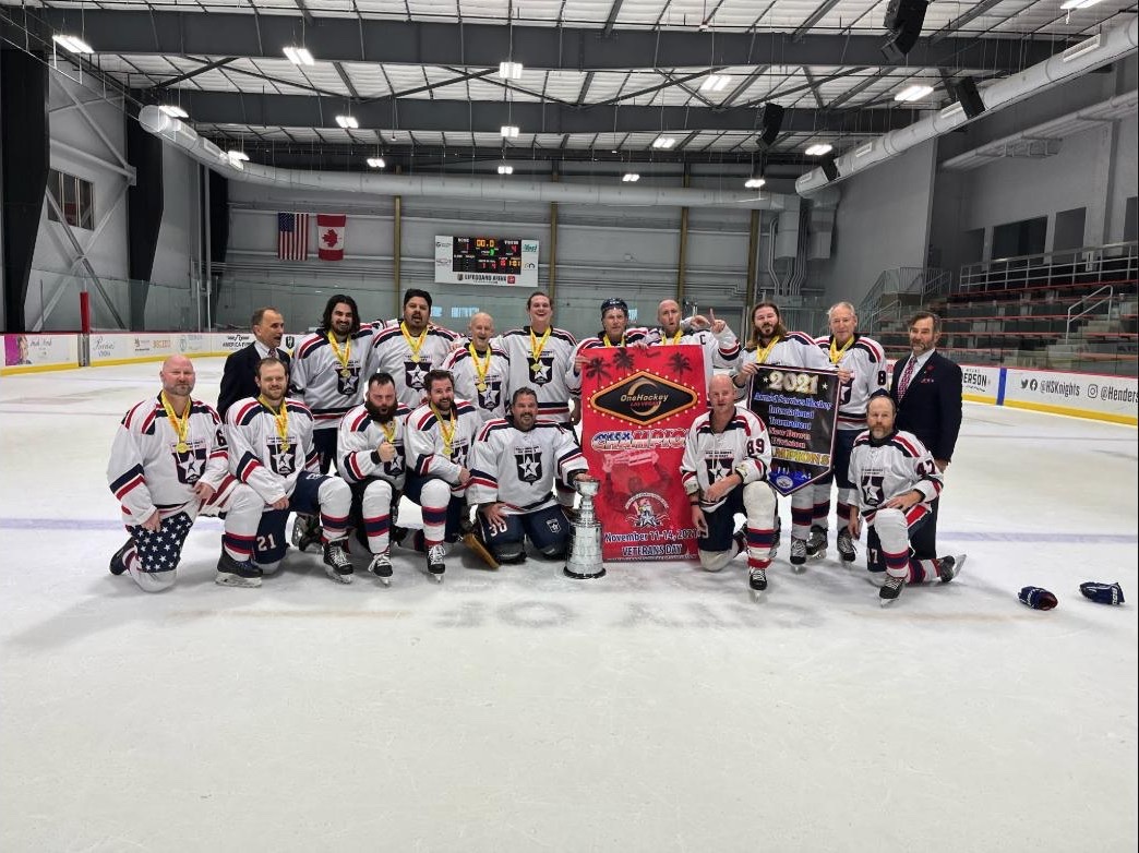 OneHockey adult tournament champions — Las Vegas — the USA Warriors team in white with medals and the cup on the ice